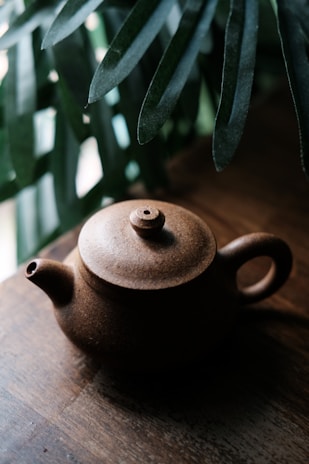 A close-up of tea leaves and a teapot on a rustic surface.