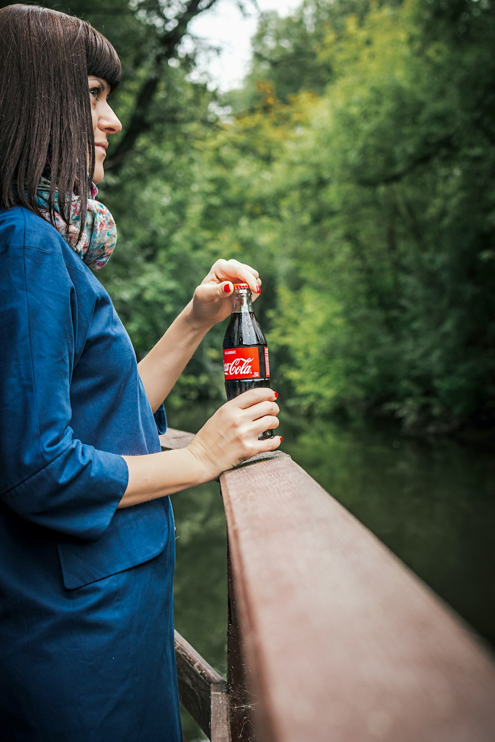 smiling woman standing and holding Coca-Cola soda bottle