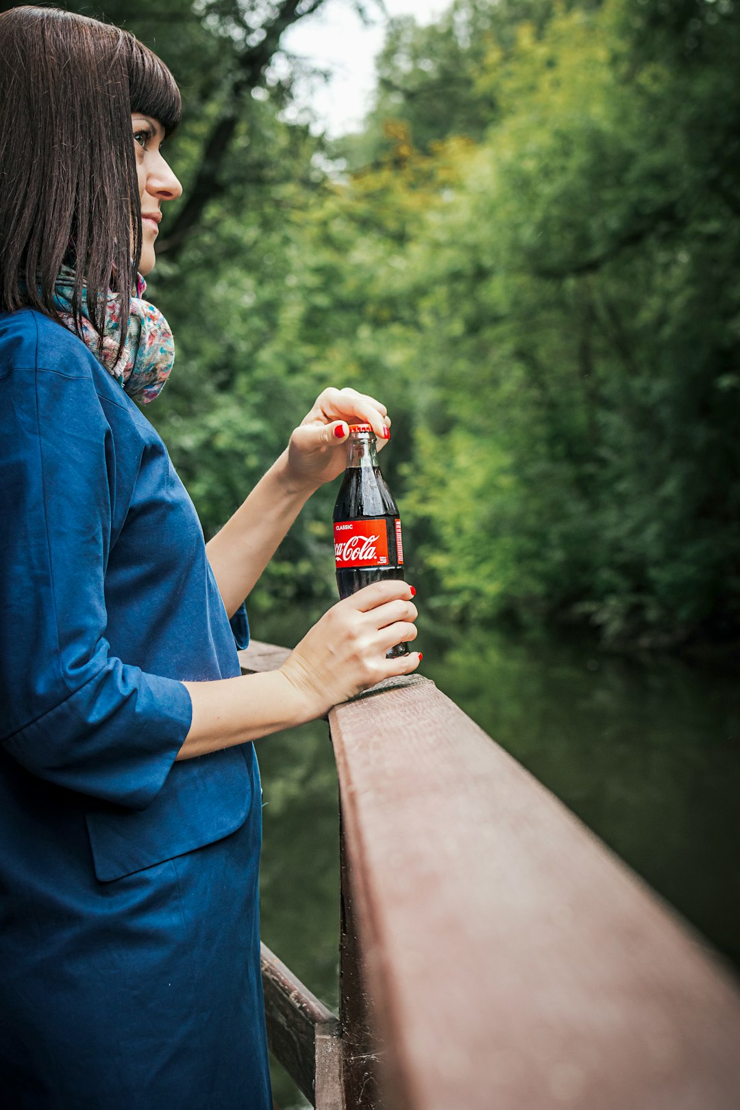 smiling woman standing and holding Coca-Cola soda bottle