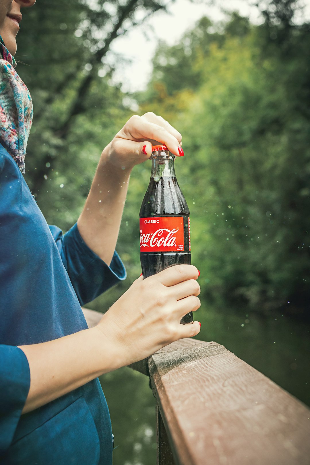 person holding Coca Cola bottle near railings