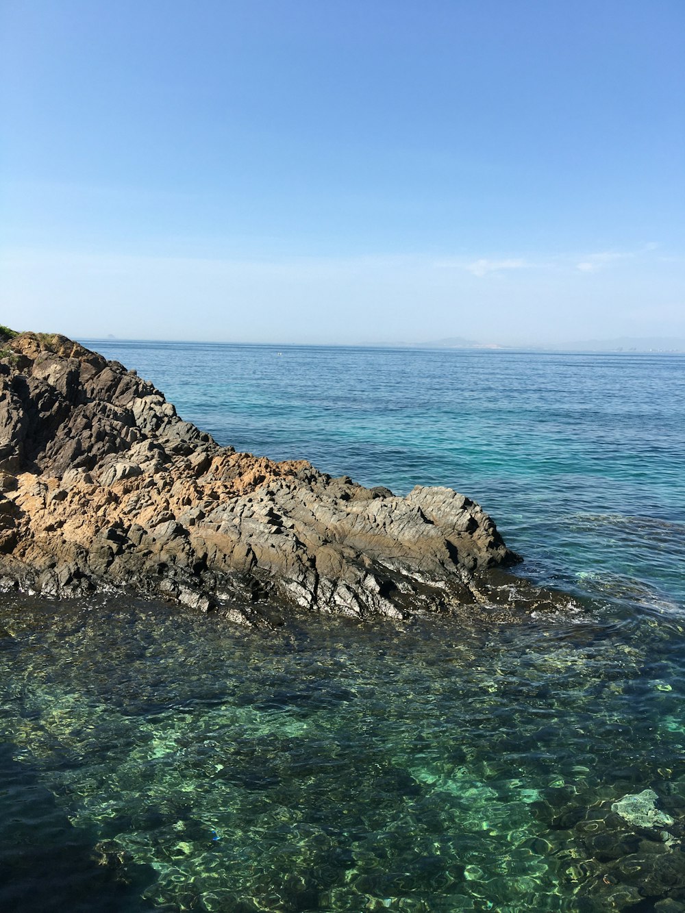 Formazione rocciosa sull'acqua limpida dell'oceano durante il giorno