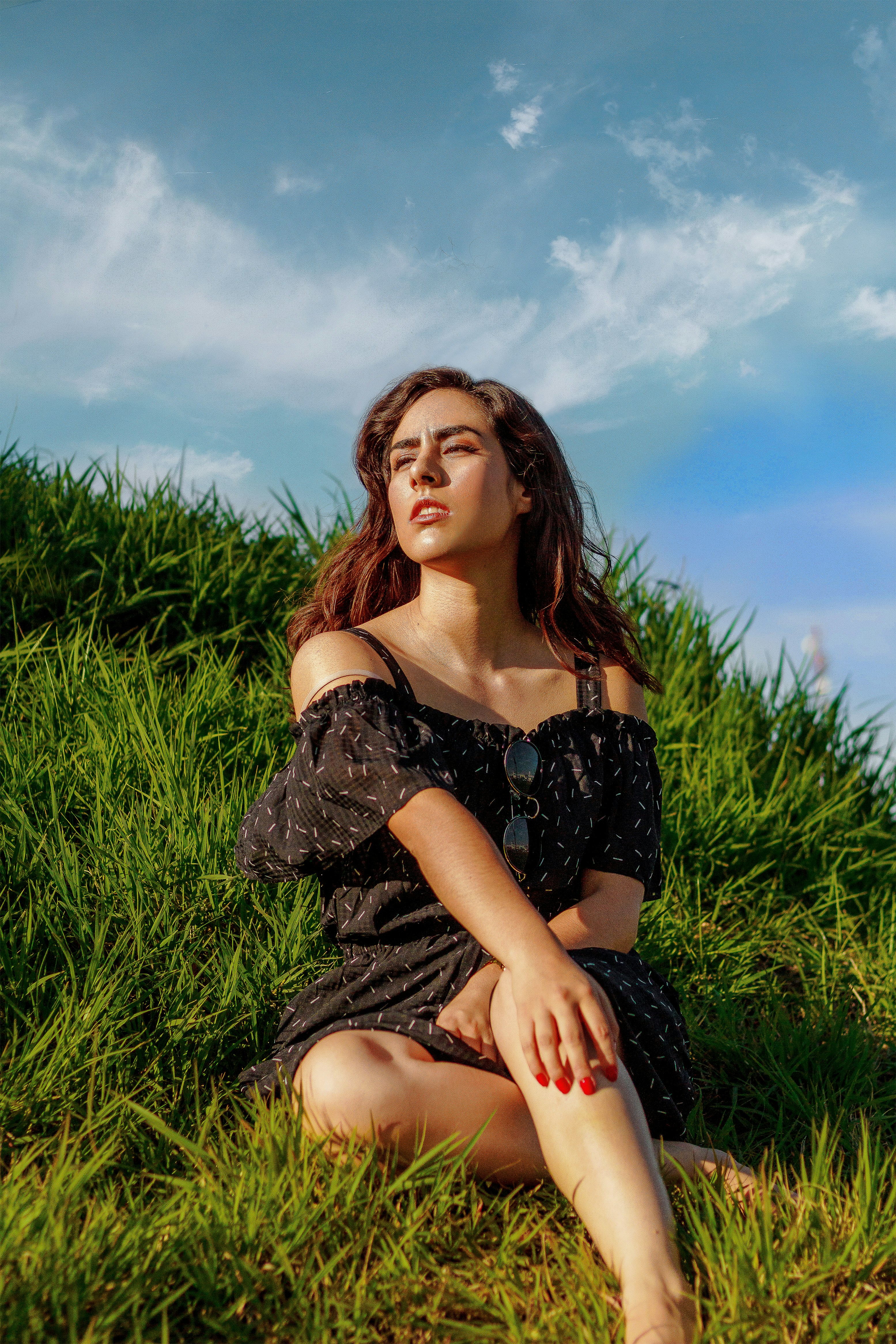 woman in black off-shoulder shirt sitting on grass during daytime