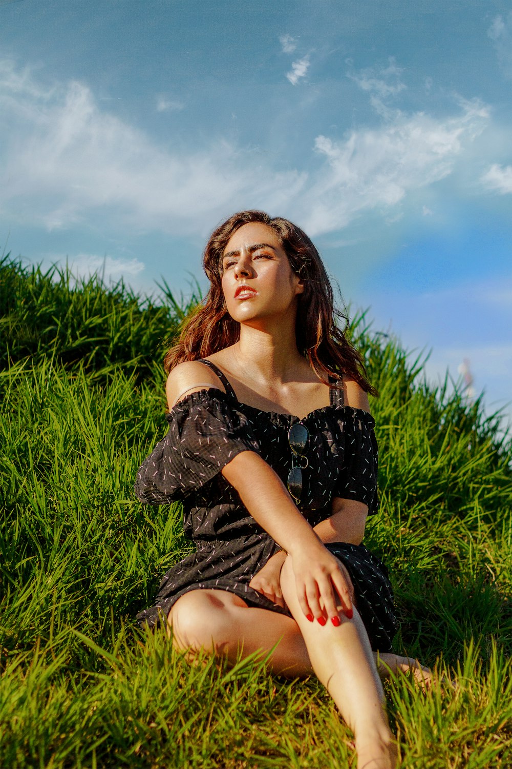 woman in black off-shoulder shirt sitting on grass during daytime