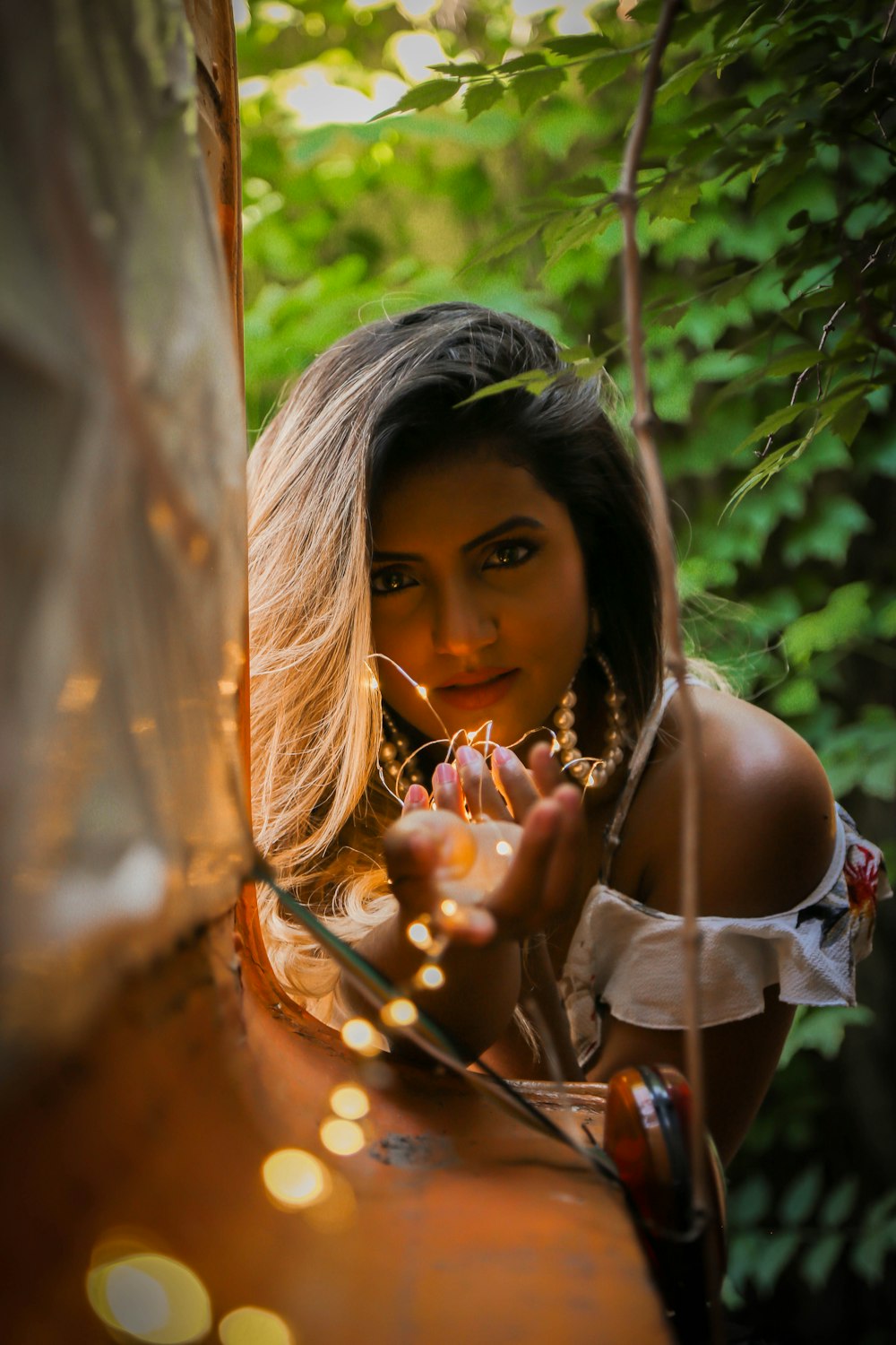 woman in white cold-shoulder blouse holding string lights