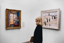 Femme dans une galerie d'art, admirant une peinture parmi des tableaux contemporains de maîtres.