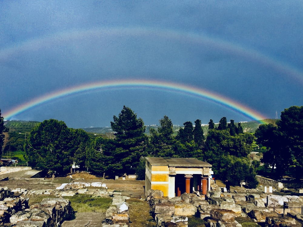 aerial photo of buildings and trees under rainbow and clear blue sky during daytime