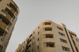 High-rise residential buildings with modern architectural design. The structures feature multiple floors with balconies and windows. The facade is composed of neutral-colored materials, giving it a sleek and sophisticated look.