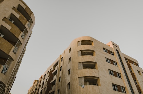 High-rise residential buildings with modern architectural design. The structures feature multiple floors with balconies and windows. The facade is composed of neutral-colored materials, giving it a sleek and sophisticated look.