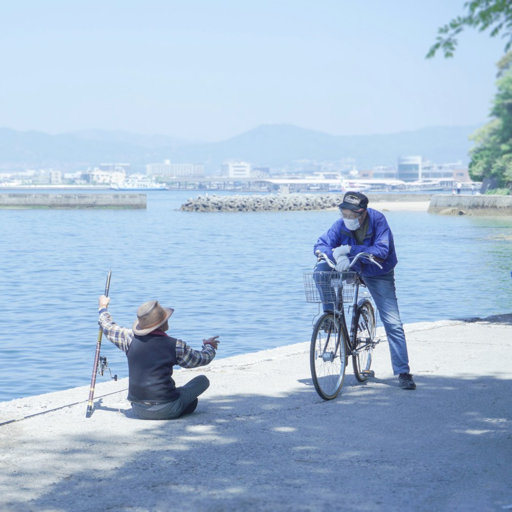 a man sitting on a bench next to a man on a bike