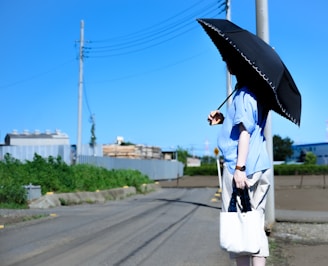 person in blue t-shirt and white pants standing near road