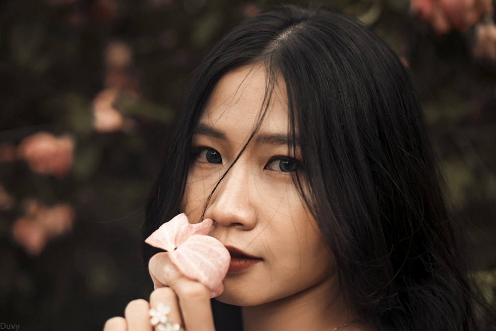 woman kissing on pink-petaled flower