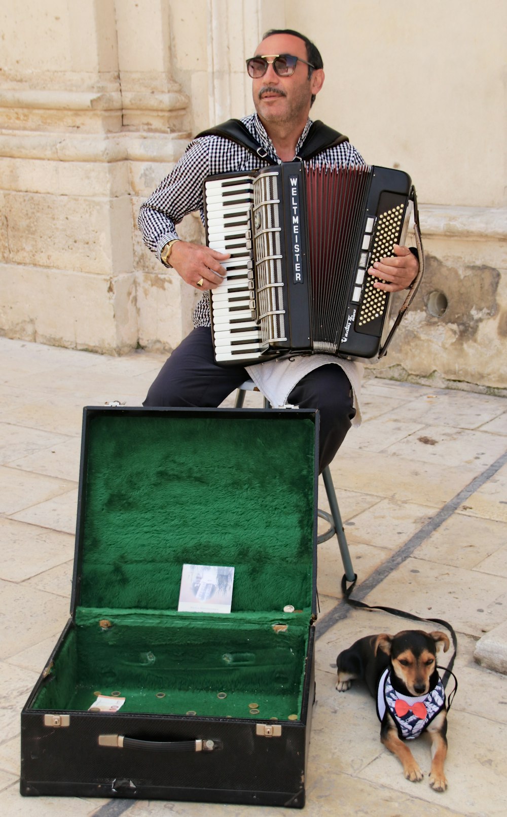man playing accordion sitting beside dog