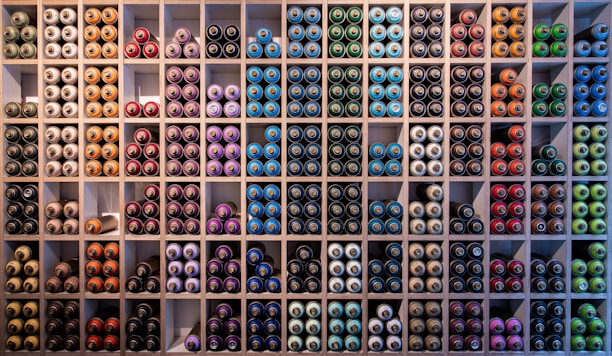Bright photo of colorful paint cans arranged on wooden shelves in a store