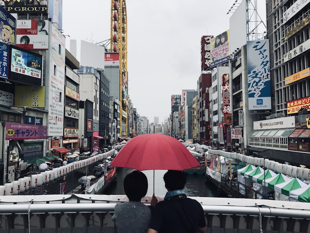 two person under red umbrella
