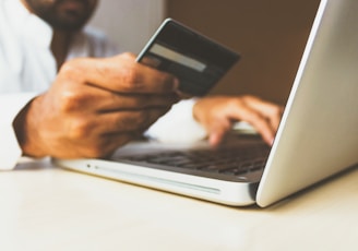 person using laptop computer holding card