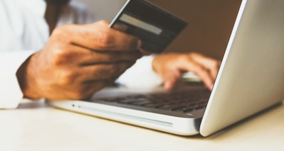 person using laptop computer holding card