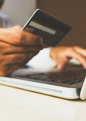 person using laptop computer holding card