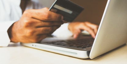 person using laptop computer holding card