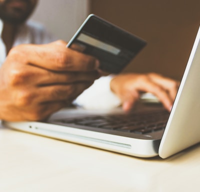 person using laptop computer holding card