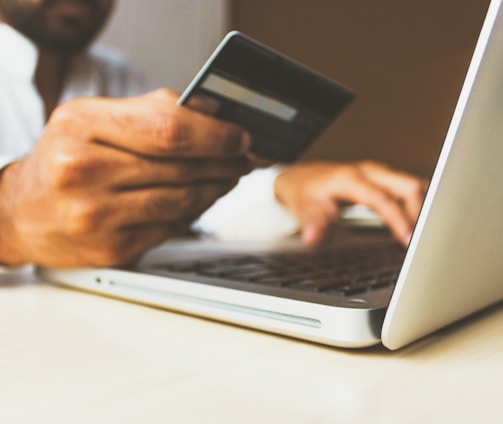 person using laptop computer holding card