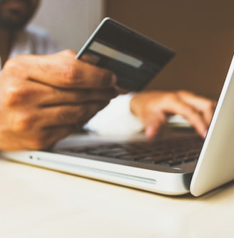 person using laptop computer holding card