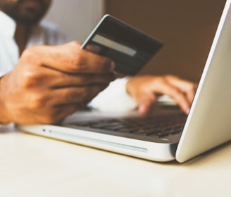 person using laptop computer holding card