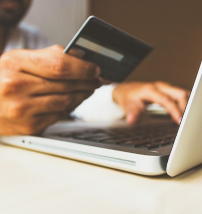 person using laptop computer holding card