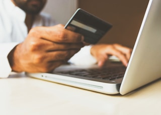 person using laptop computer holding card