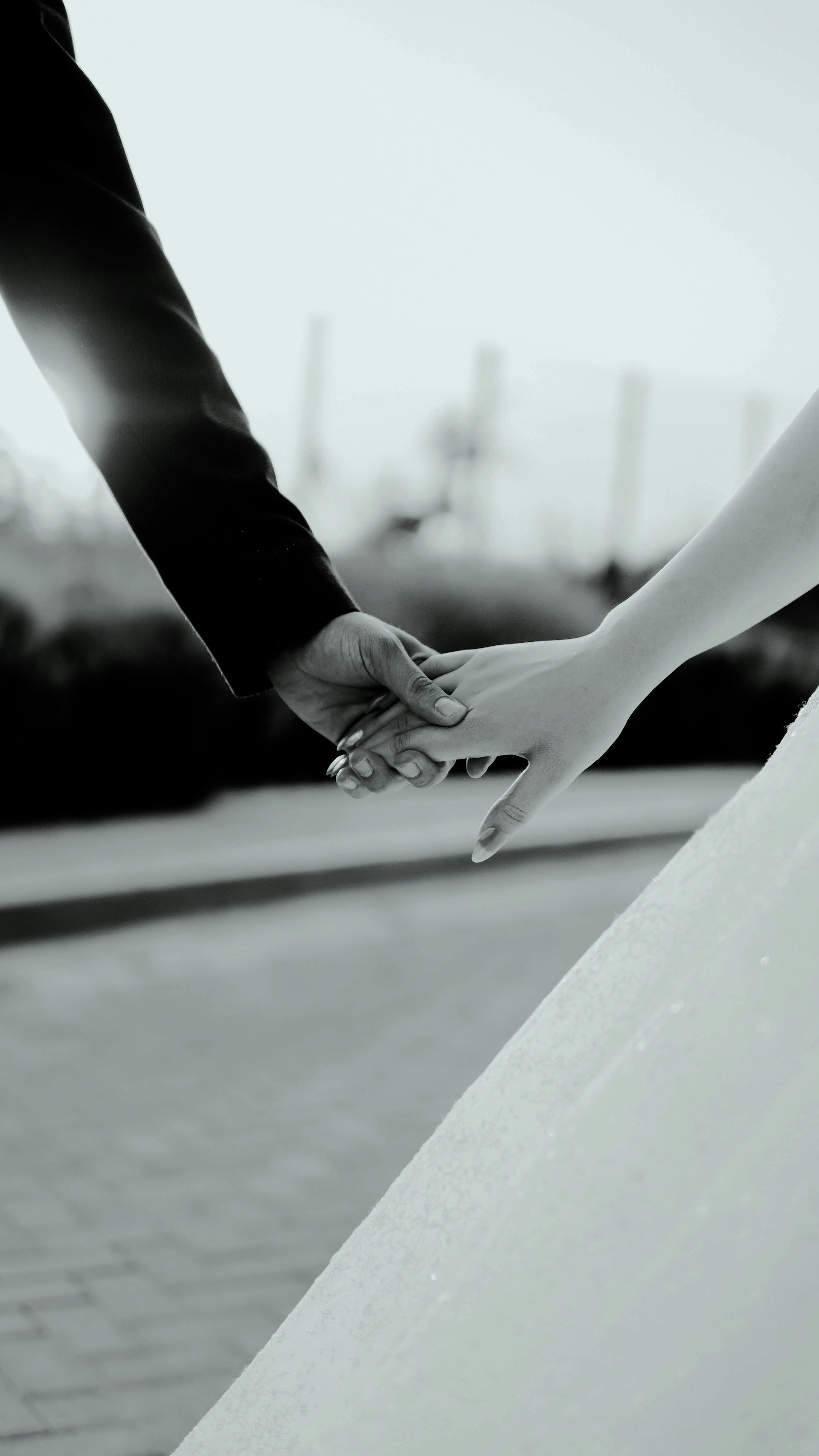 a bride and groom hold hands as they walk down the street