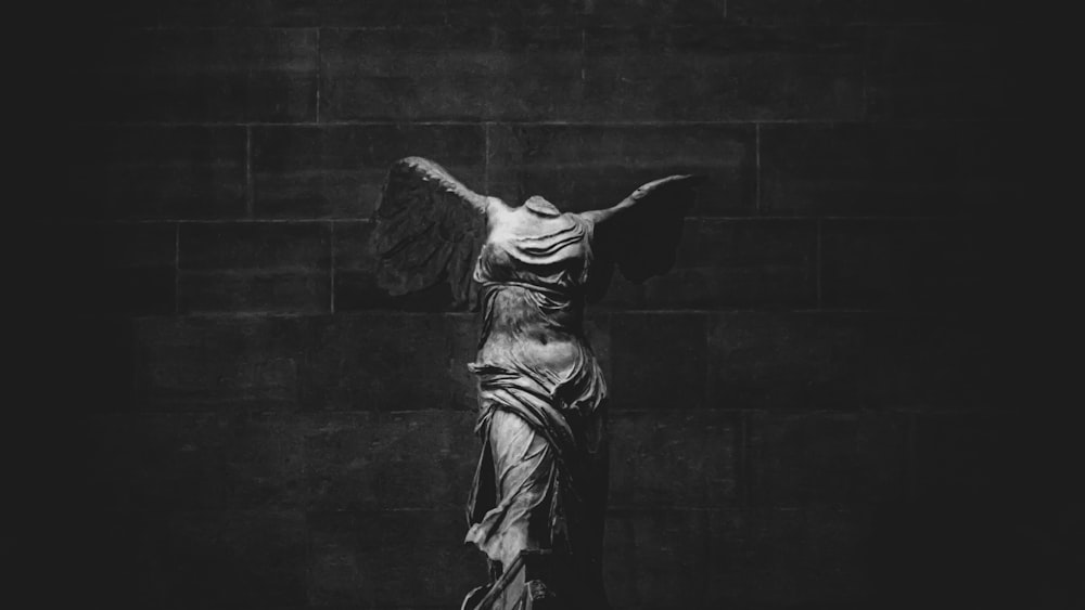 woman in dress statue near grey concrete wall