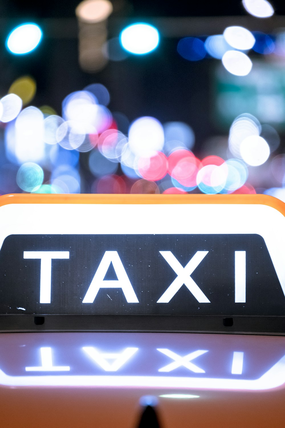 Eine Nahaufnahme eines Taxischildes mit verschwommenen Lichtern im Hintergrund