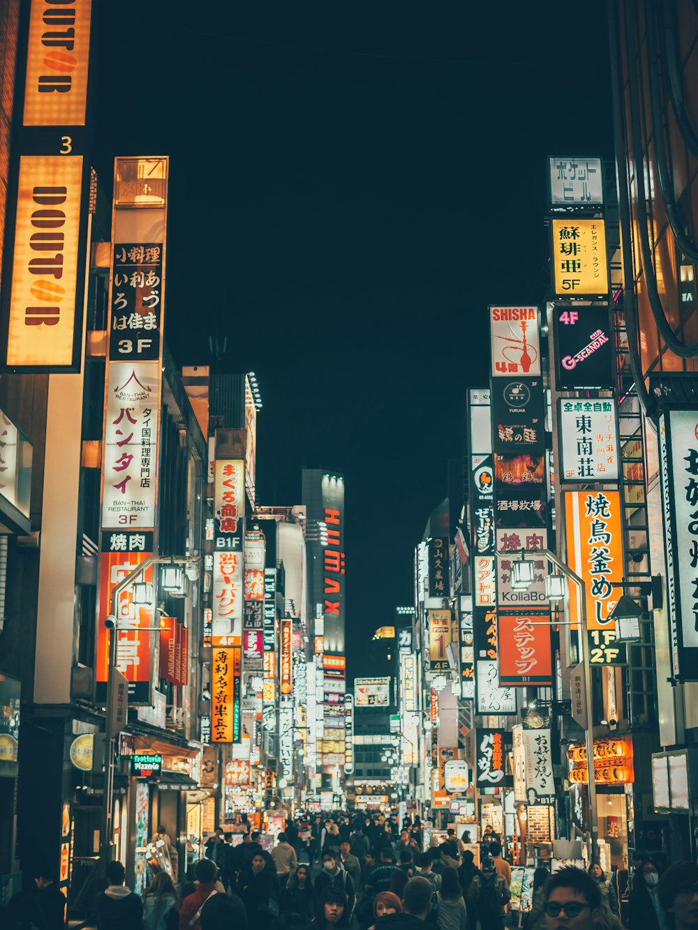 personas caminando entre edificios durante la noche