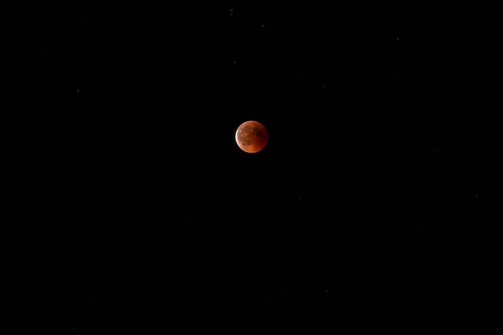 a red moon is seen in the dark sky