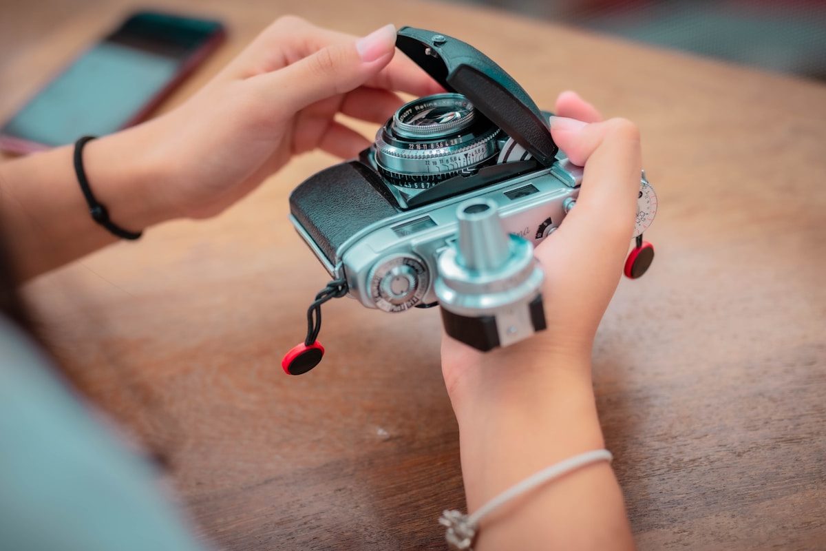 A person holding a camera on a wooden table
