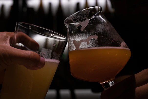 Close-up of frothy beer glasses clinking together, capturing the golden bubbles and joyful cheers.