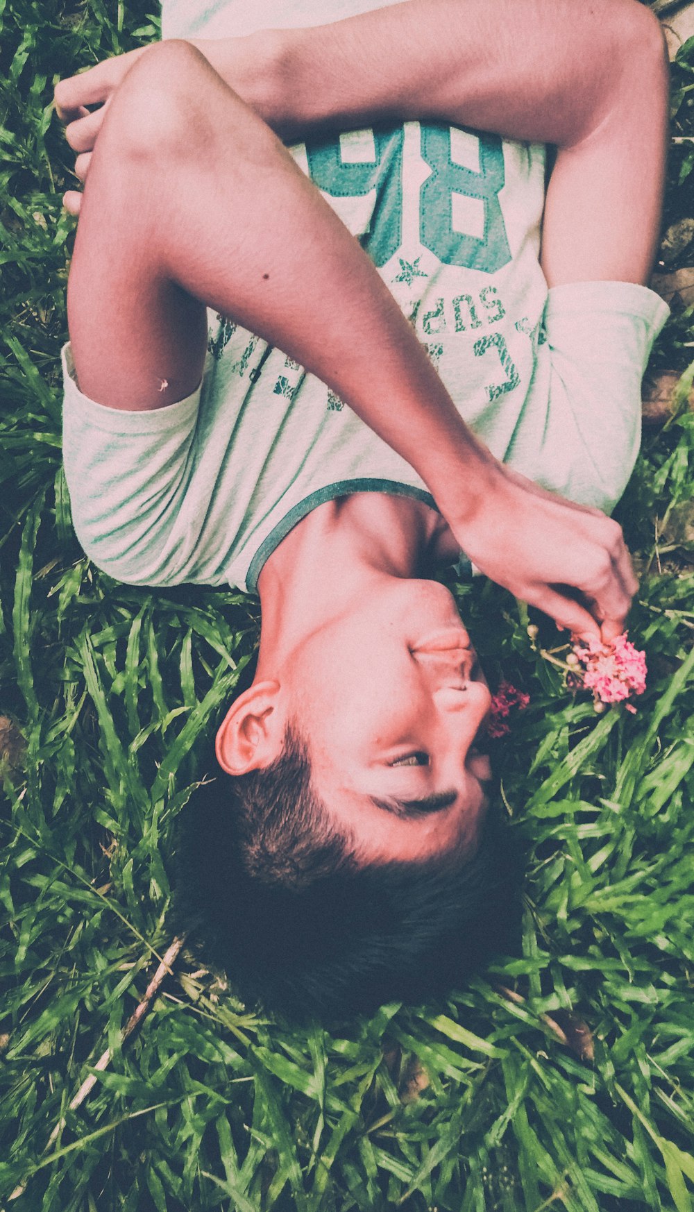 boy in white and green crew-neck t-shirt lying on ground
