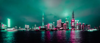 A vibrant cityscape at dusk with sleek modern architecture illuminated by teal and white lights.