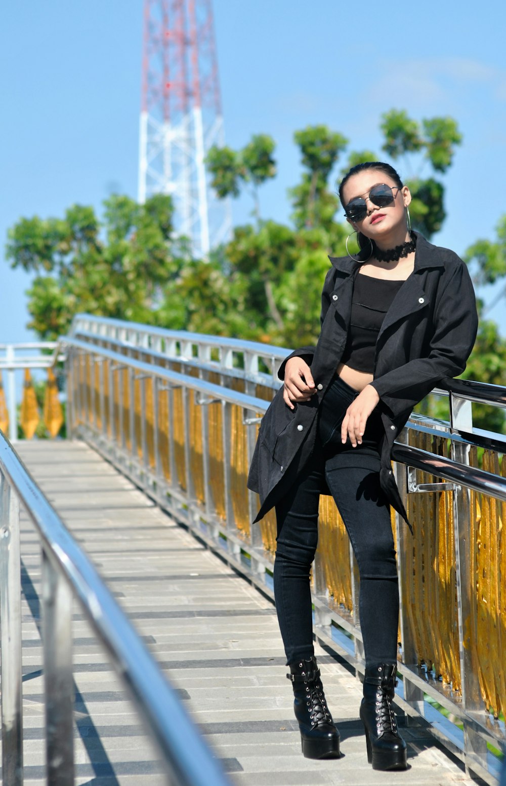 woman in black blazer and black pants posing near railings