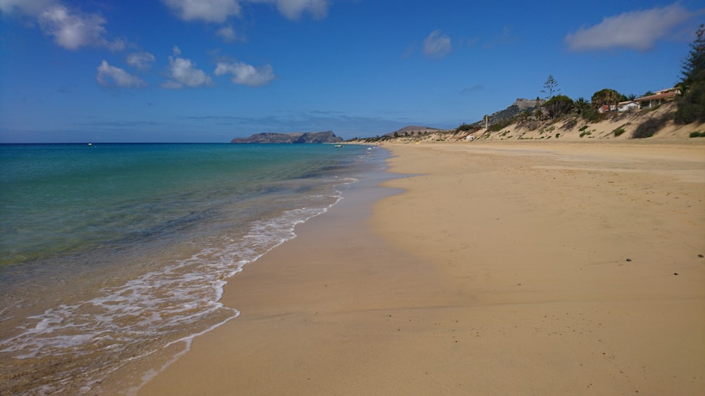 a sandy beach with clear blue water on a sunny day