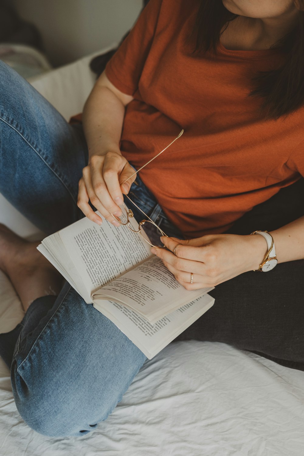 woman sits on bed while reading book