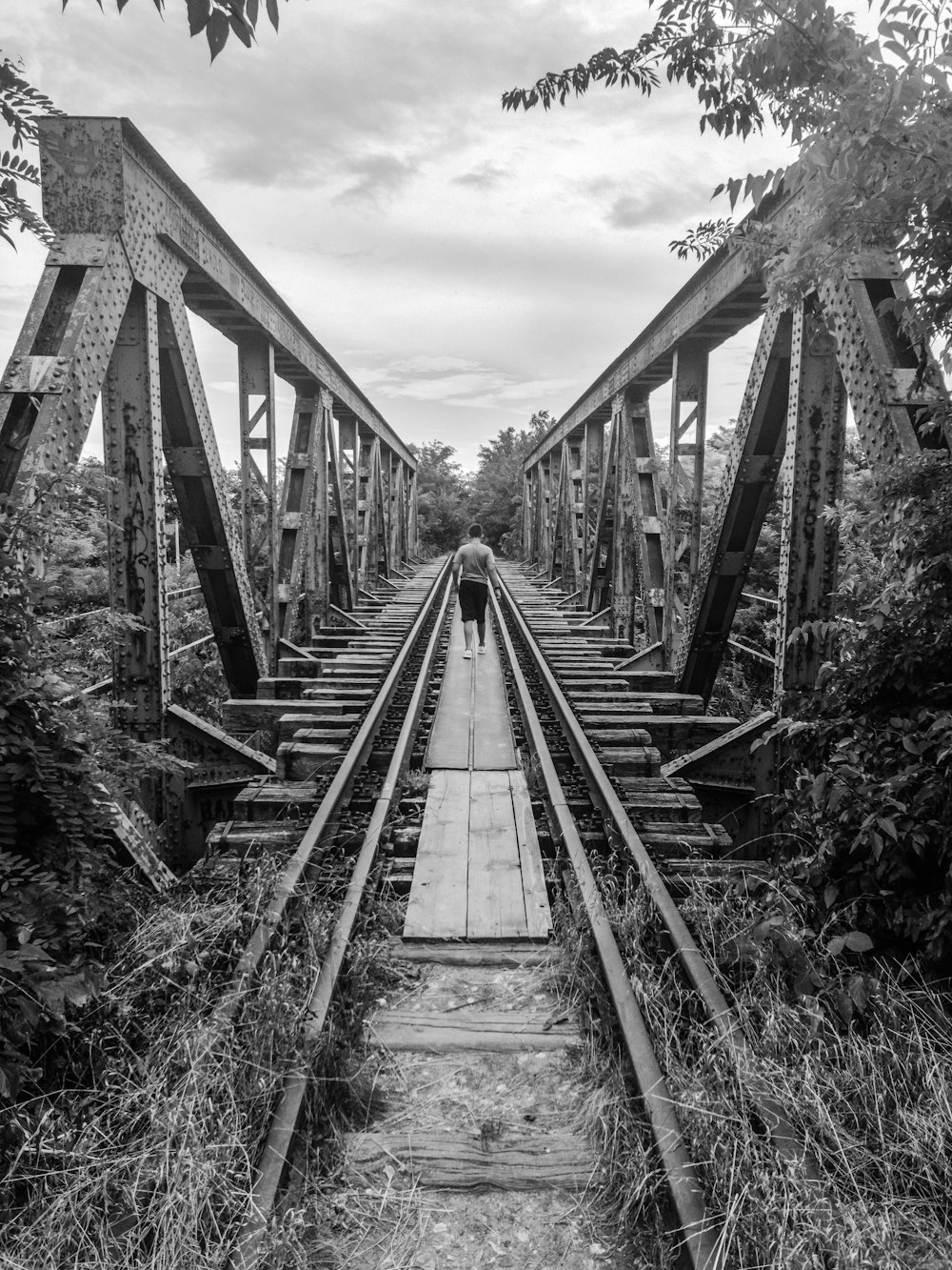 grayscale photography of man on bridge