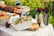 Close-up of a hand pouring golden olive oil over a fresh salad in a bright kitchen.