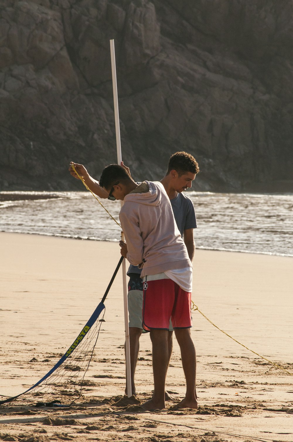 a couple of people standing on top of a sandy beach