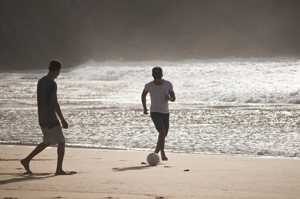 men playing football in beach