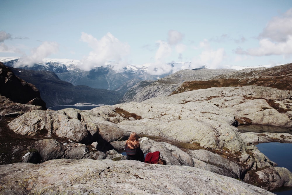 person sitting on rock near body of water