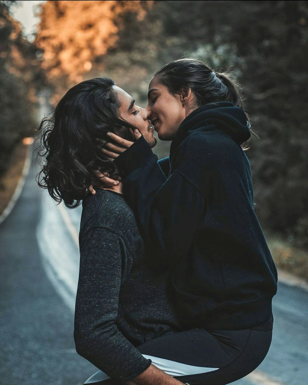 man and woman kissing and standing on road