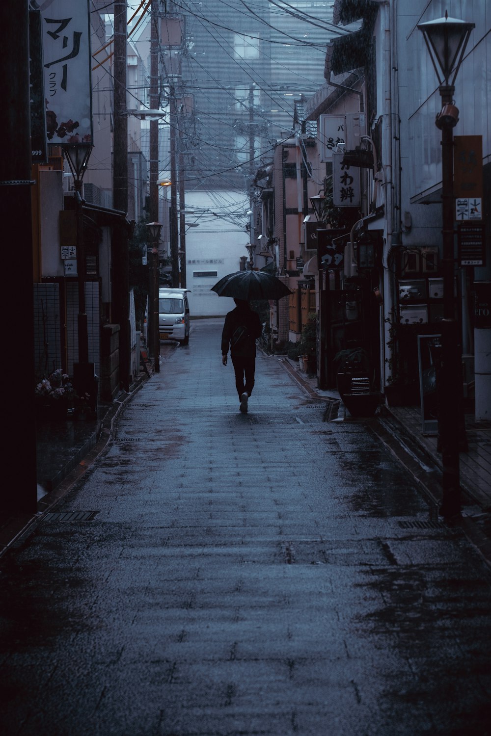 man holding umbrella walking on hallway between buildings