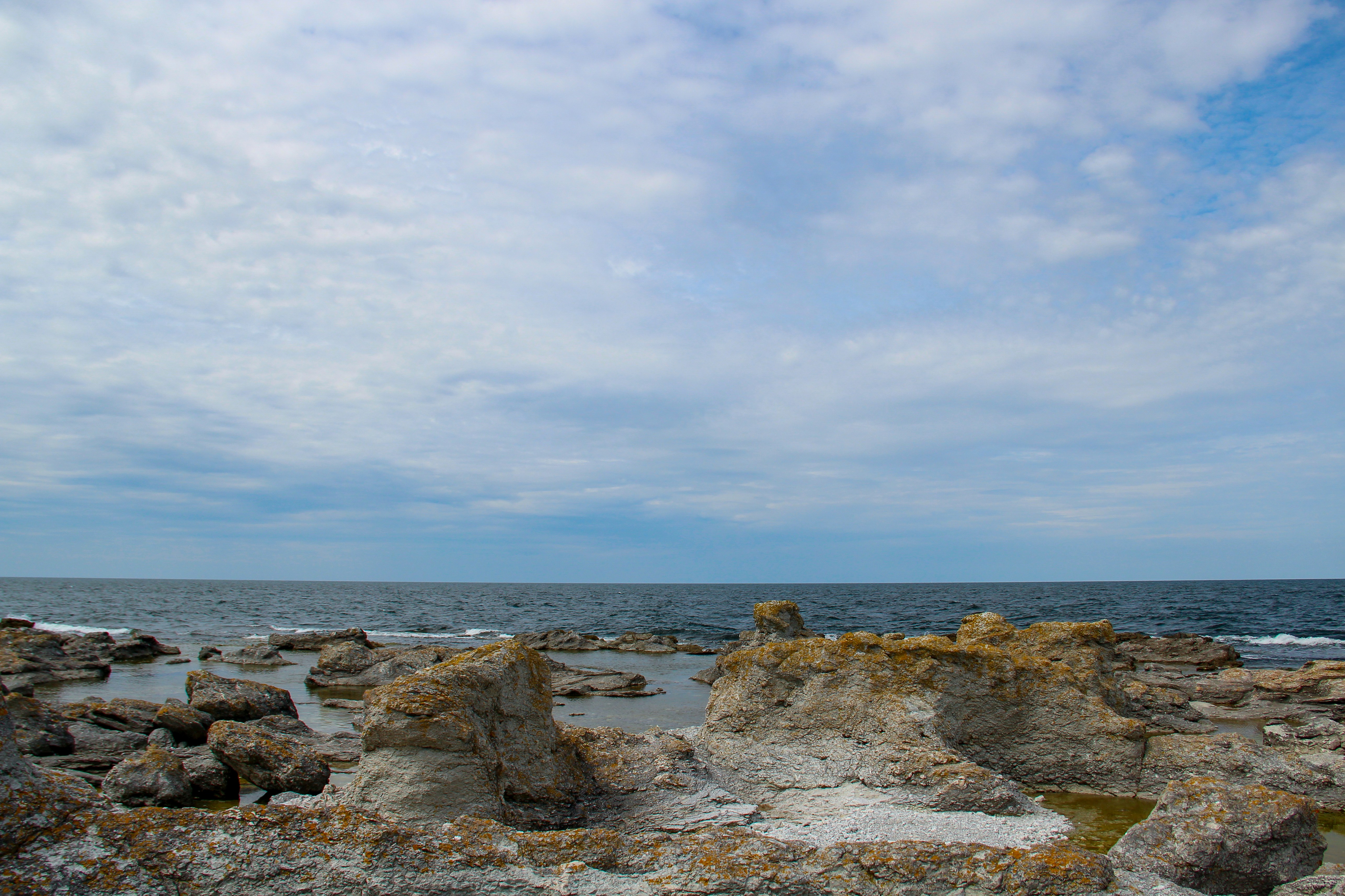 seashore during daytime, A rock formation with a beautiful sky!