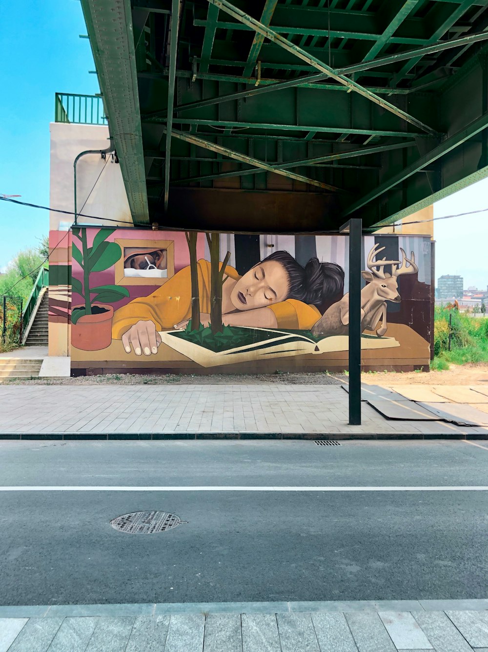a mural on the side of a building under a bridge