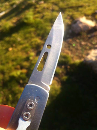 A smiling customer holding a perfectly sharpened pocket knife outdoors.